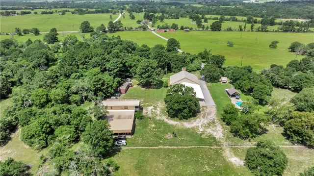an aerial view of residential houses with outdoor space and trees
