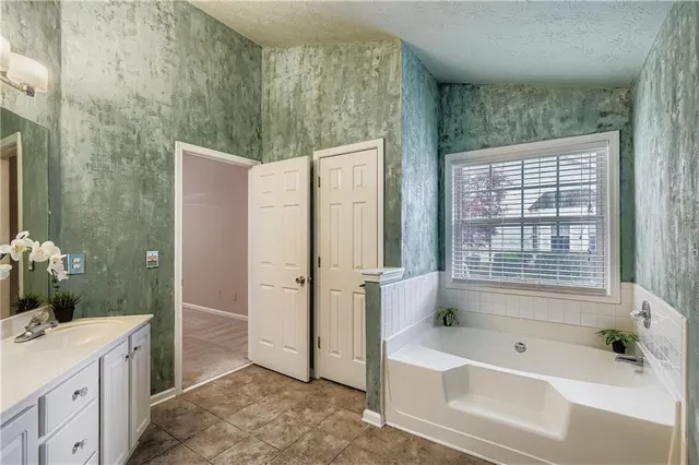 a bathroom with a tub a sink and a large mirror