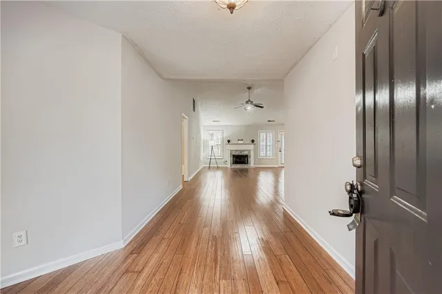 an empty room with wooden floor fan and windows