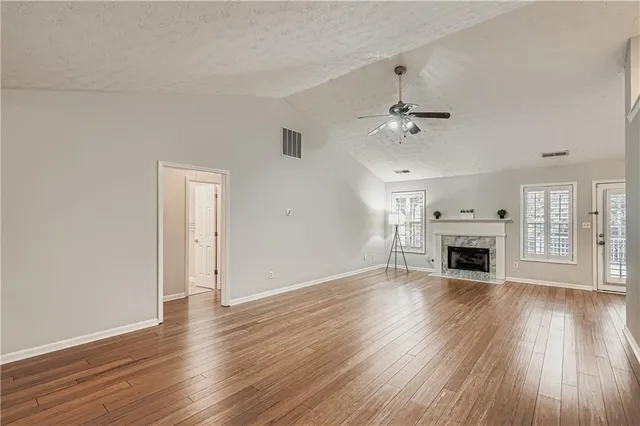 a view of a livingroom with wooden floor a fireplace and windows