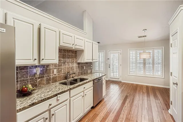a kitchen with granite countertop stainless steel appliances a sink window and cabinets