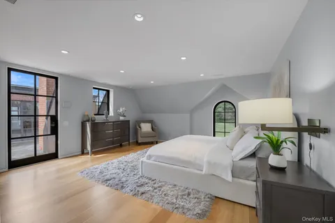a bedroom with a bed a dresser and potted plants with wooden floor