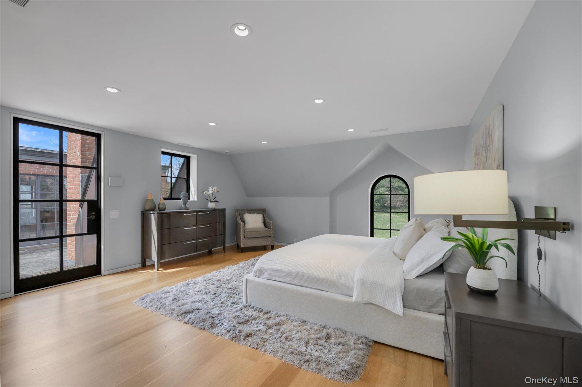 217 Sands Point Road Sands Point, NY 11050 - Photo 24 of 39 a bedroom with a bed a dresser and potted plants with wooden floor