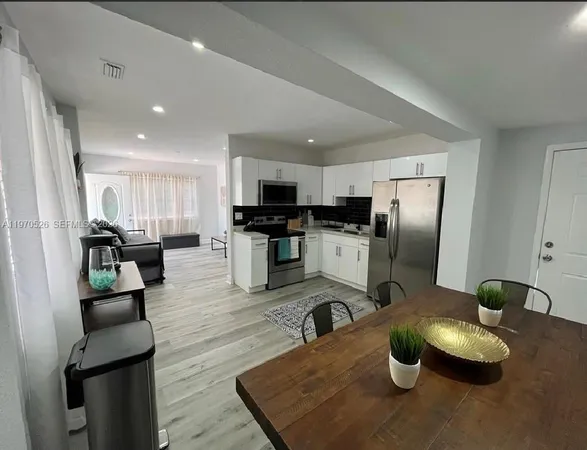 a kitchen with stainless steel appliances granite countertop a refrigerator a stove a sink dishwasher a dining table and chairs with wooden floor