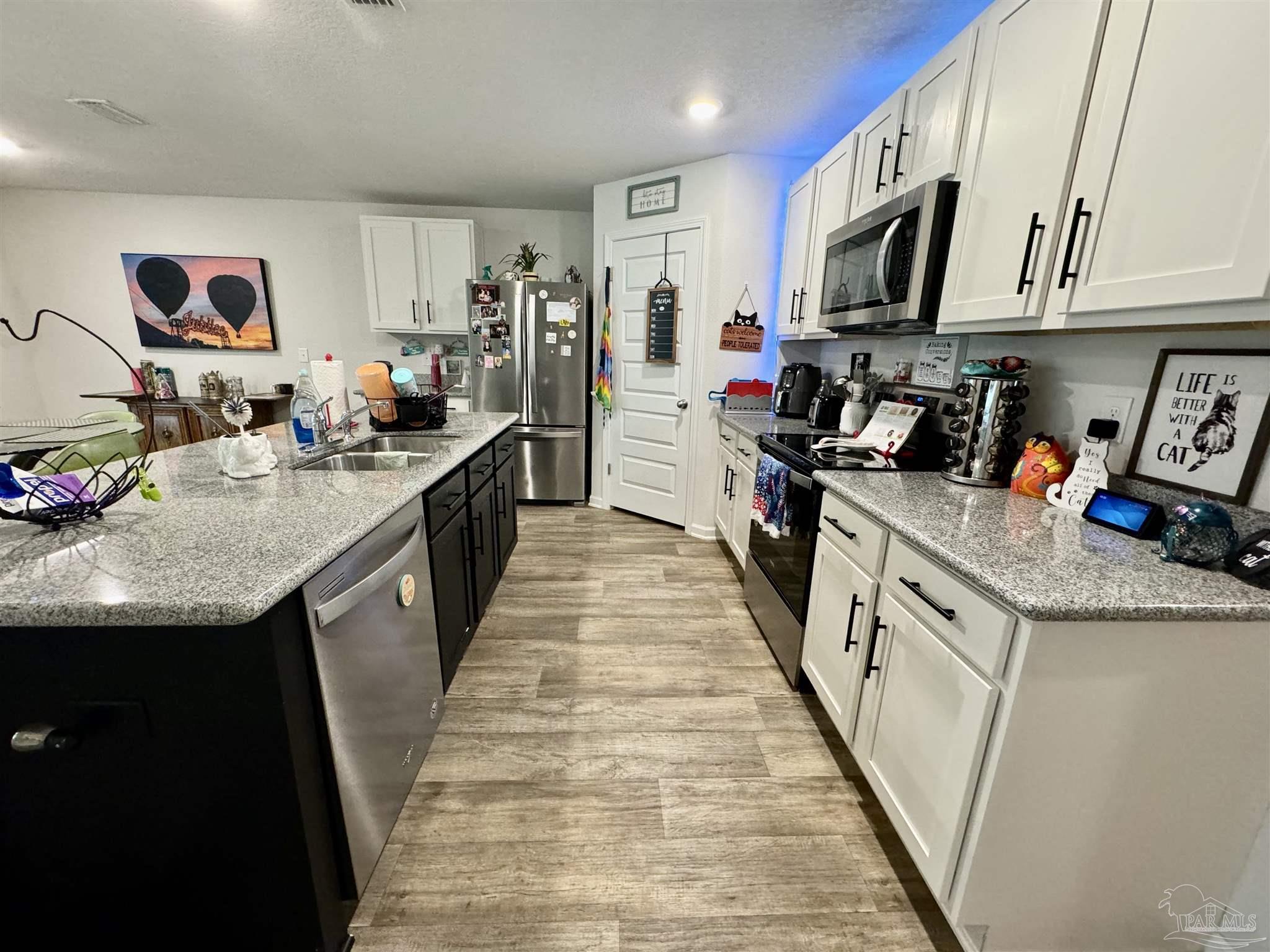 5645 Guinevere Lane Milton, FL 32583 - Photo 13 of 24 a kitchen with kitchen island granite countertop lots of counter top space and stainless steel appliances
