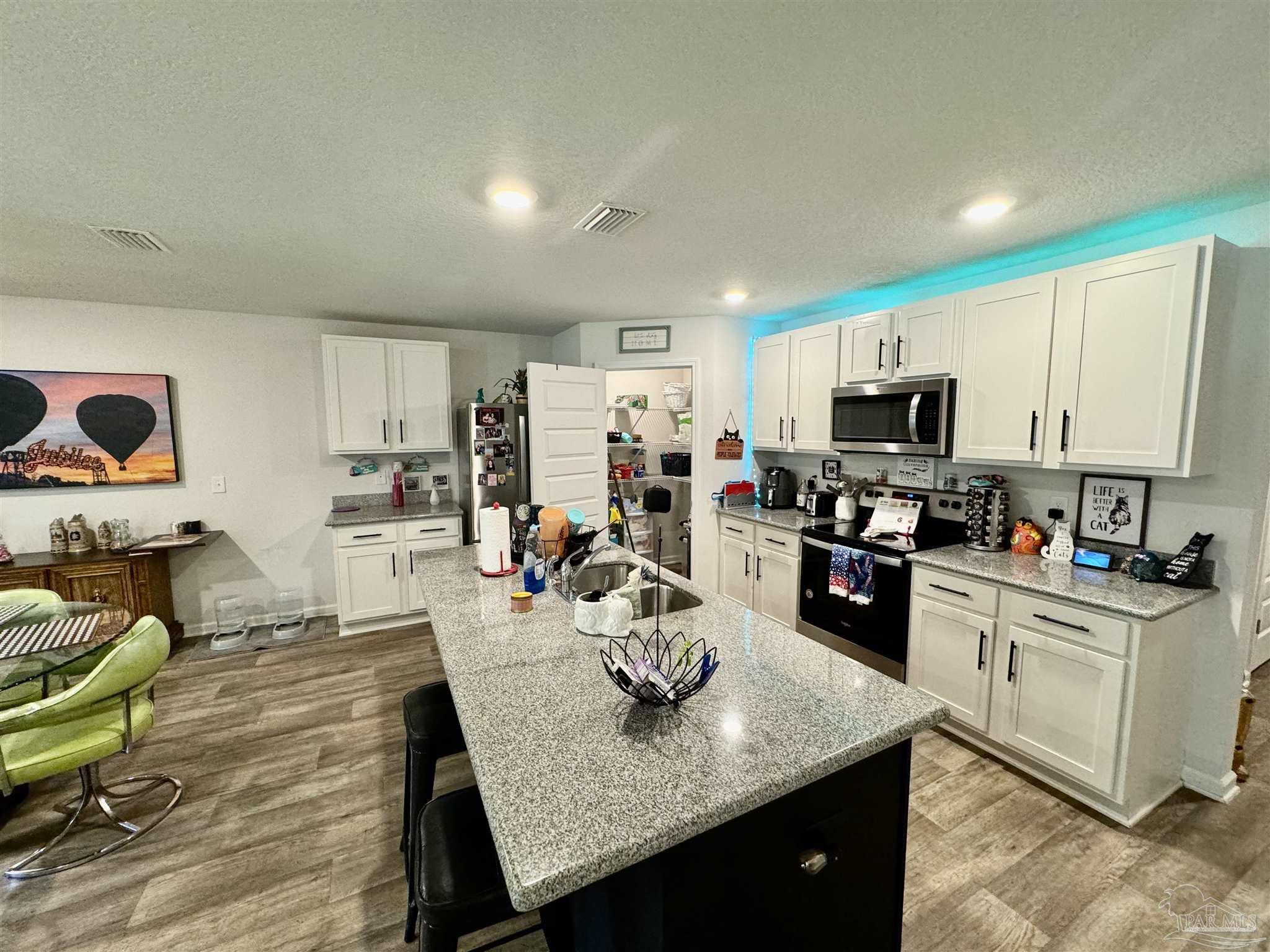 5645 Guinevere Lane Milton, FL 32583 - Photo 14 of 24 a kitchen with a sink a stove and chairs