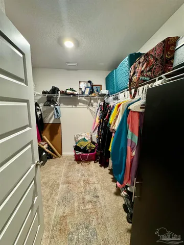 a view of walk in closet with clothes and shoes