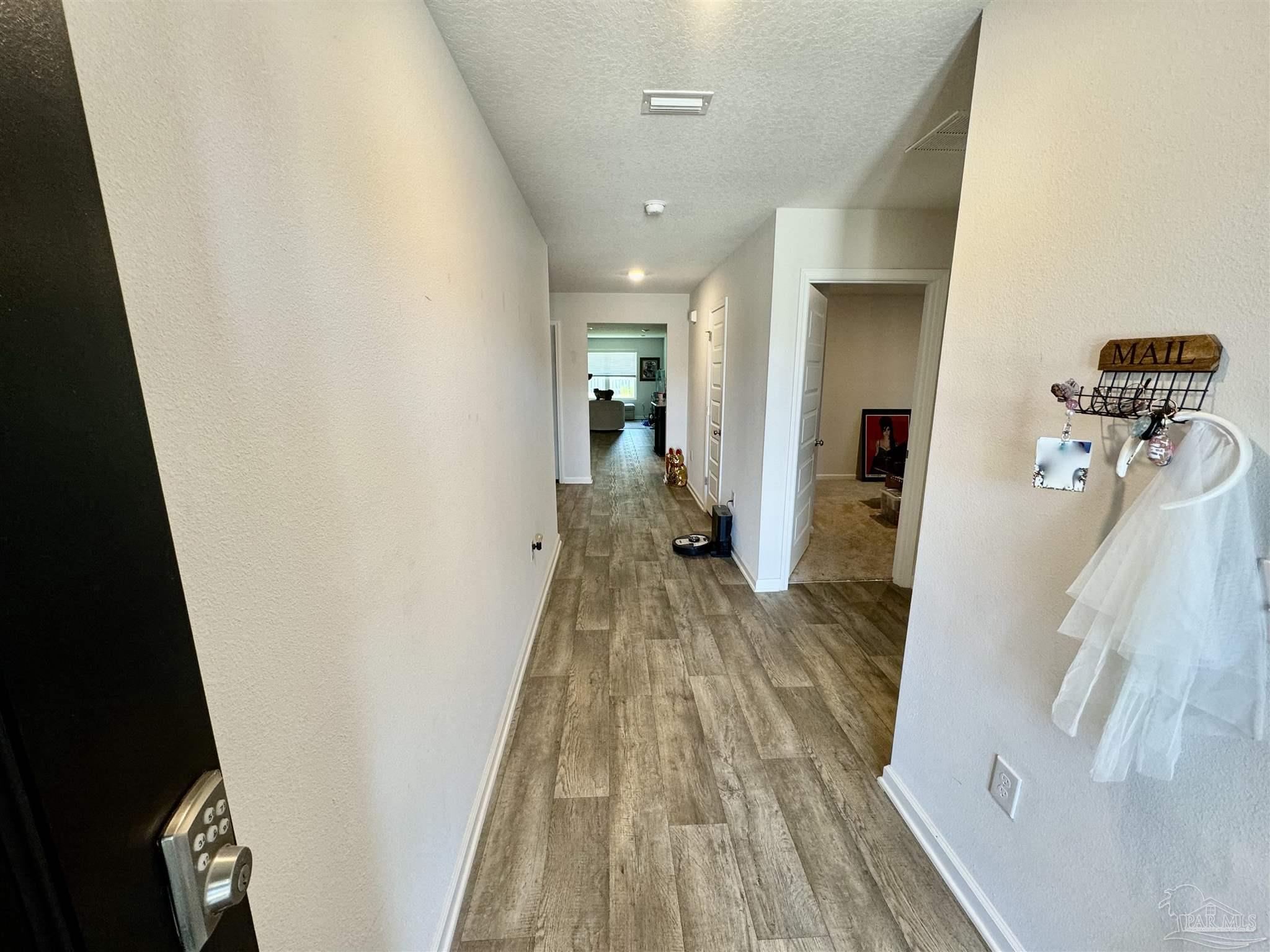 5645 Guinevere Lane Milton, FL 32583 - Photo 4 of 24 a view of a hallway with wooden floor and staircase