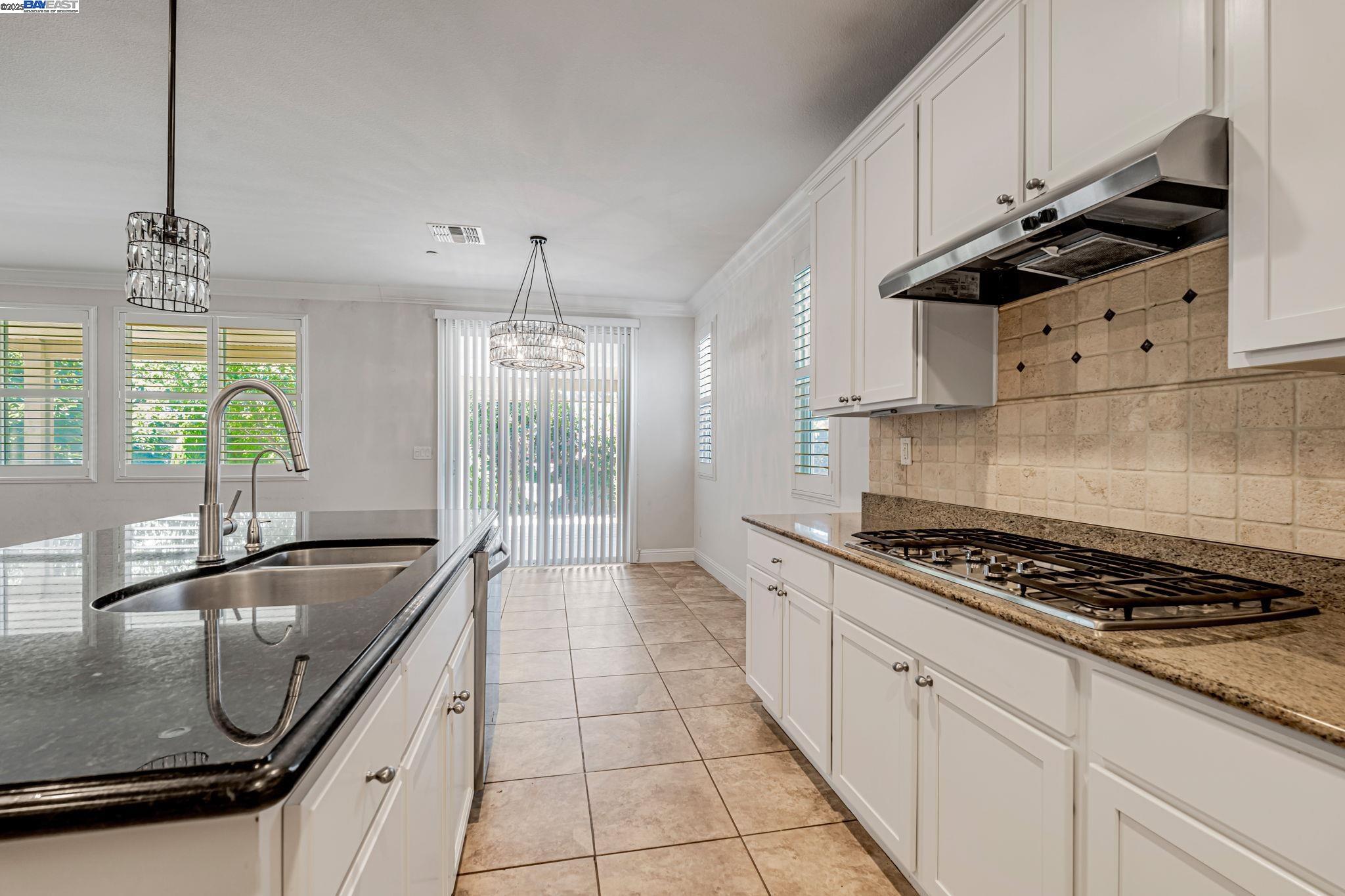 2491 Redbud Way Manteca, CA 95336 - Photo 3 of 27 a kitchen with granite countertop a sink a counter space appliances and cabinets
