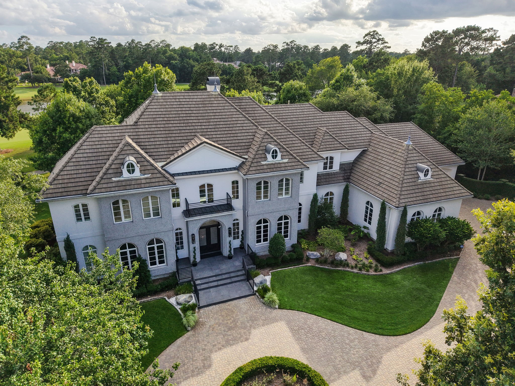 39 Maymont Way Spring, TX 77382 - Photo 4 of 50 This stunning home features elegant architecture with a grand entrance, multiple gables, and dormer windows. It is surrounded by lush landscaping and a circular driveway, offering privacy and luxury in a serene setting.