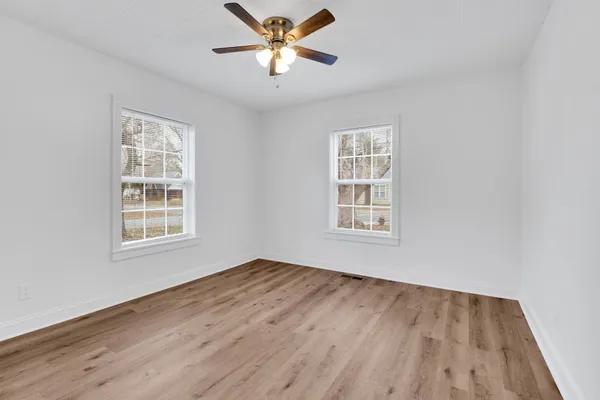 a view of an empty room with window and wooden floor