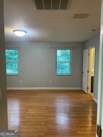 an empty room with wooden floor and windows