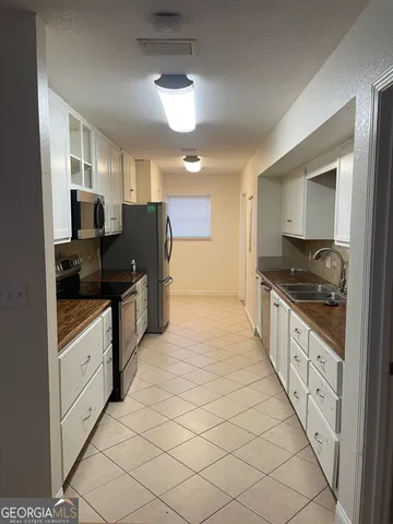 a kitchen with granite countertop white cabinets stainless steel appliances and a sink