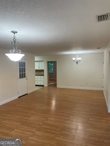 a view of an empty room with a window and a kitchen
