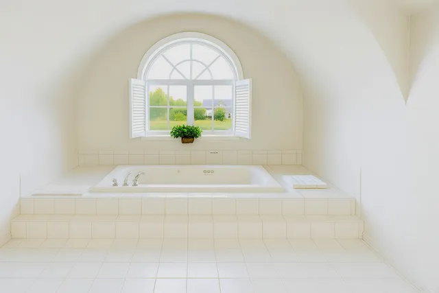 a bath tub sitting in a bathroom next to a window