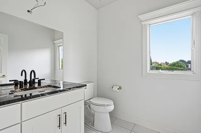a bathroom with a granite countertop toilet a sink and a mirror