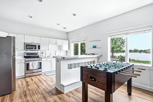 a kitchen with stainless steel appliances kitchen island granite countertop a stove top oven a sink dishwasher a dining table and chairs with wooden floor
