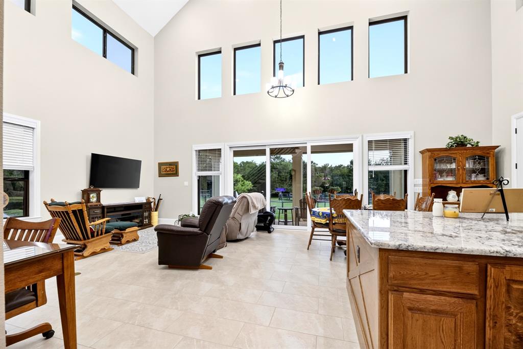 985 Vest Lane Pilot Point, TX 76258 - Photo 29 of 40 Vaulted ceiling living area featuring high transom windows, large format tile flooring, and a sliding glass door providing access to the exterior