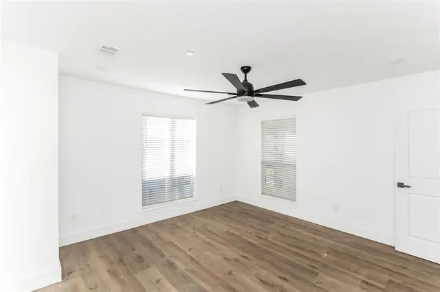 an empty room with wooden floor and windows