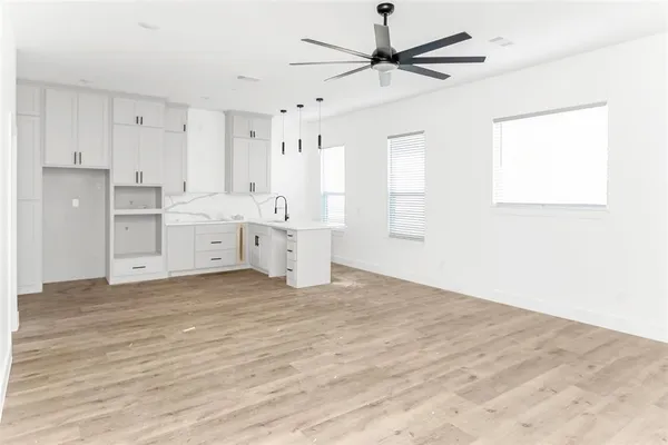 a large white kitchen with a stove a sink dishwasher and a refrigerator with wooden floor
