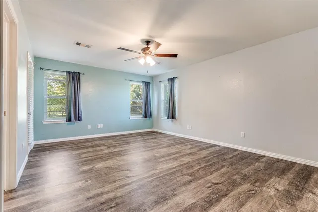 a view of an empty room with window and wooden floor