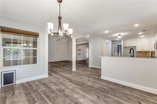a view of a big room with wooden floor and windows