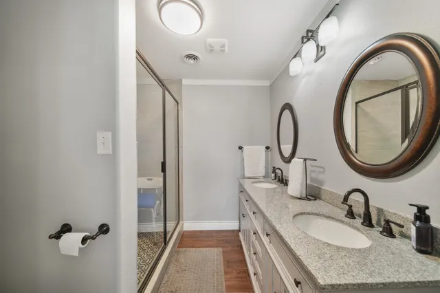 a bathroom with a granite countertop sink a mirror and a shower