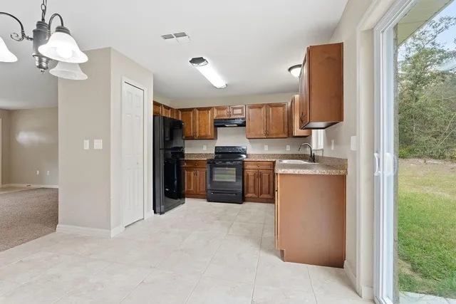 a kitchen with stainless steel appliances granite countertop a refrigerator a oven a sink with a dining table and chairs