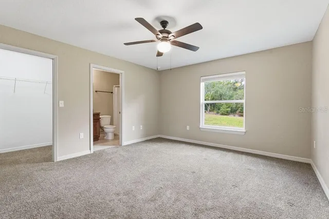 an empty room with windows and ceiling fan