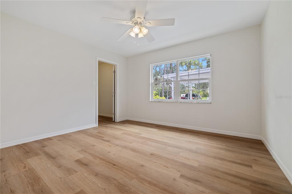 8916 Memorial Highway Tampa, FL 33615 - Photo 11 of 26 an empty room with wooden floor chandelier fan and windows