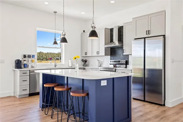 a kitchen with stainless steel appliances granite countertop a sink a stove a refrigerator and island with wooden floor