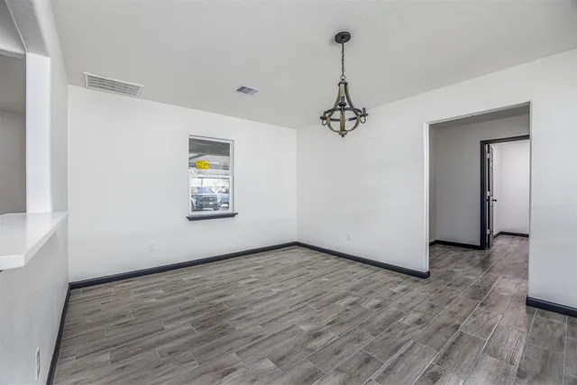 a view of an empty room with window and wooden floor