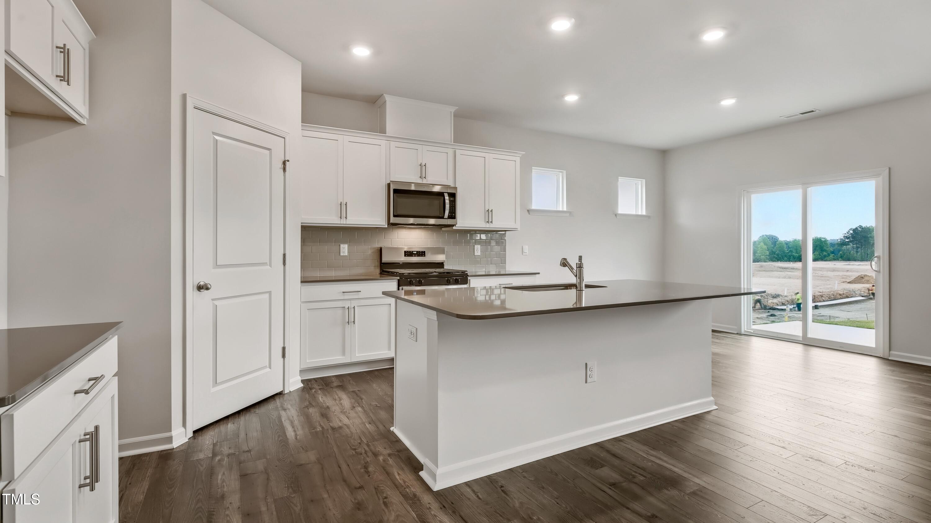 821 Comice Pear Way Willow Spring, NC 27592 - Photo 5 of 36 a kitchen with kitchen island white cabinets and wooden floor