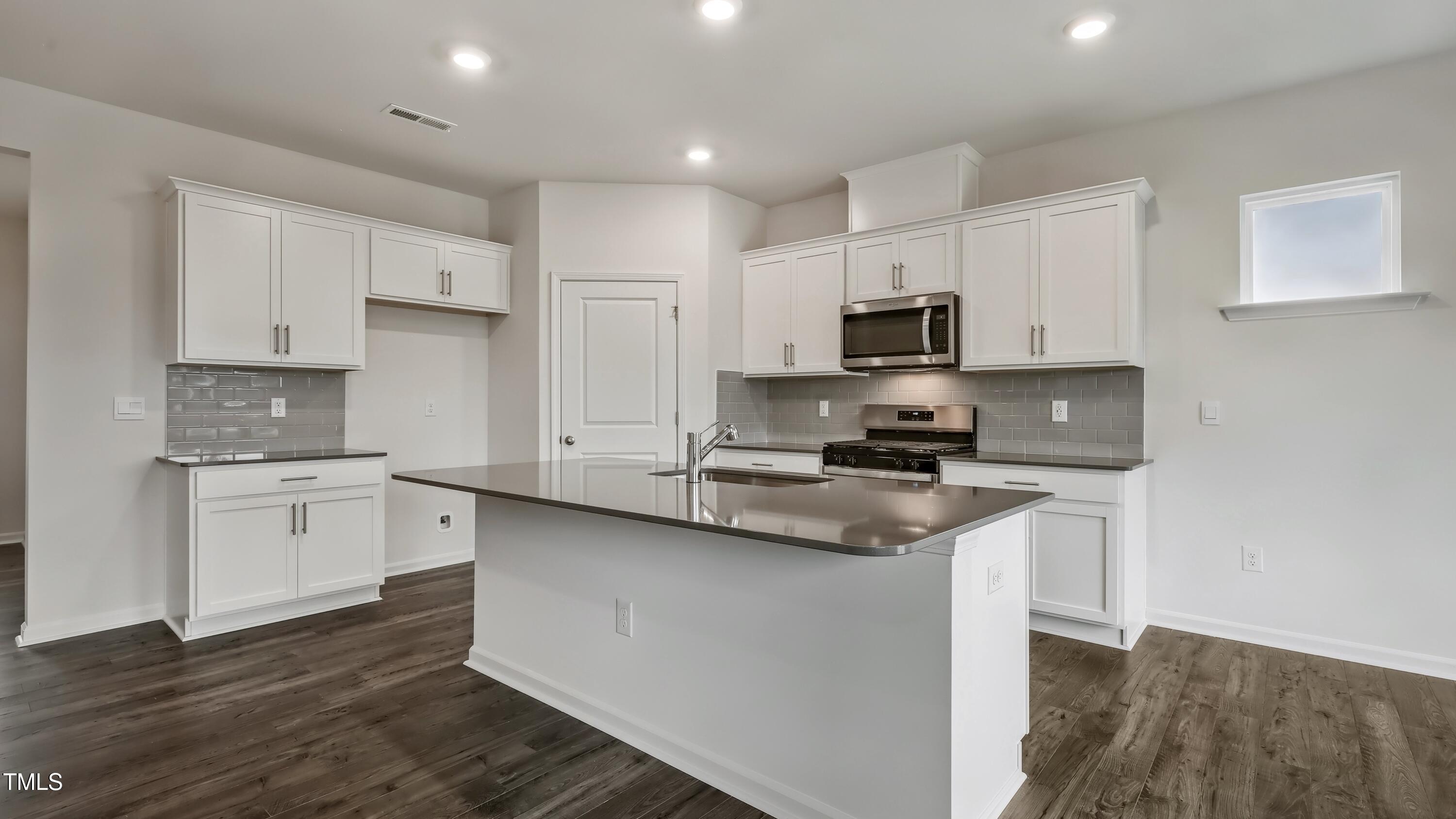 821 Comice Pear Way Willow Spring, NC 27592 - Photo 7 of 36 a kitchen with granite countertop a sink cabinets and stainless steel appliances