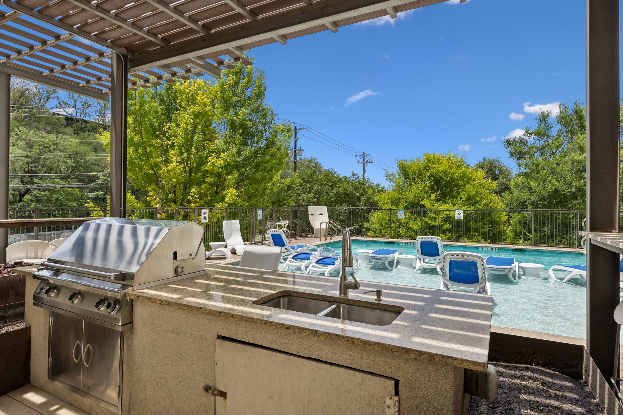 1900 Barton Springs Road, Unit 5032 Austin, TX 78704 - Photo 37 of 40 Outdoor kitchen featuring a built-in stainless steel grill and sink with a stone-finish countertop, all under a protective pergola
