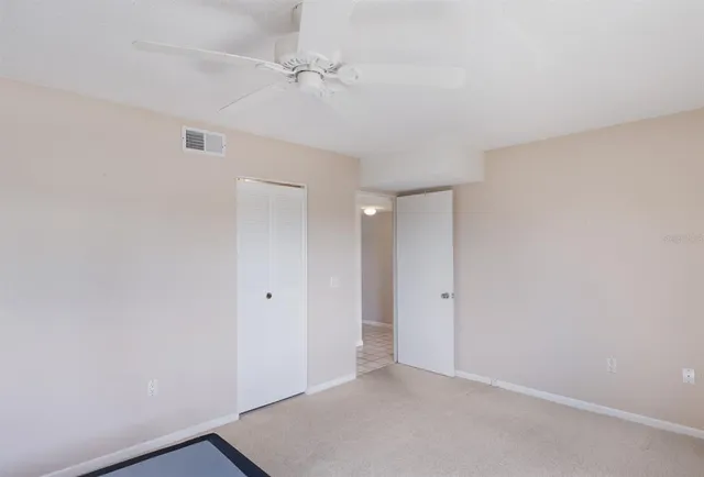 an empty room with a ceiling fan and carpet