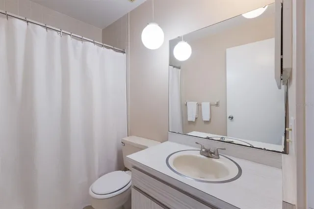 a bathroom with a sink toilet a mirror and shower curtain