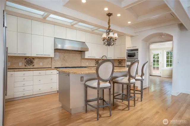 a kitchen with stainless steel appliances kitchen island granite countertop a table chairs sink and cabinets