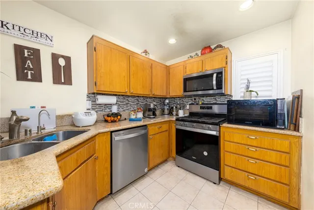 a kitchen with stainless steel appliances granite countertop a stove top oven a sink dishwasher and a microwave oven with white cabinets