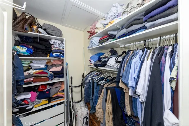 a view of walk in closet with clothes and shoes