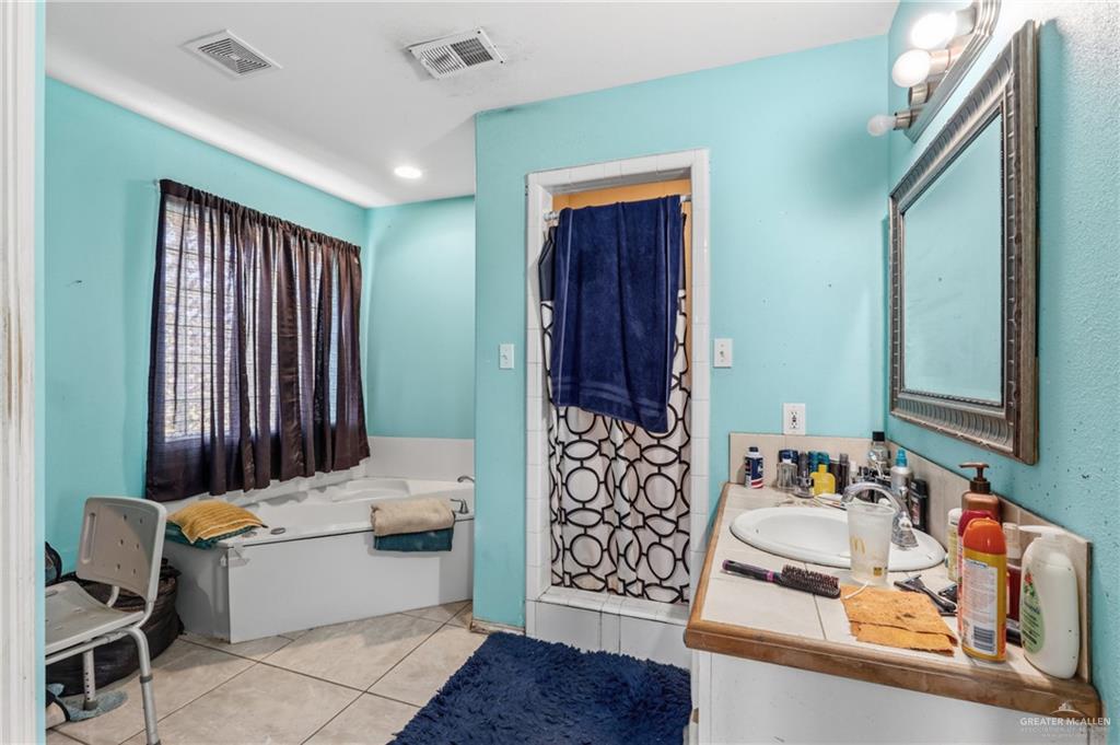 402 Mockingbird Lane Edcouch, TX 78538 - Photo 14 of 25 Bathroom featuring a built-in tub, tiled flooring, vanity with a drop-in sink, and a framed wall mirror
