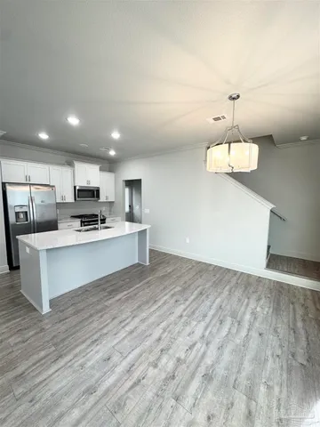 a large white kitchen with kitchen island a stove a sink dishwasher and a refrigerator with wooden floor