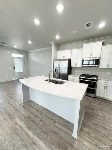 a large kitchen with stainless steel appliances a large counter top a stove and a sink
