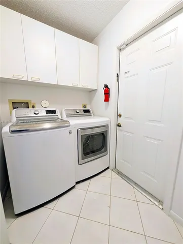 a utility room with cabinets washer and dryer