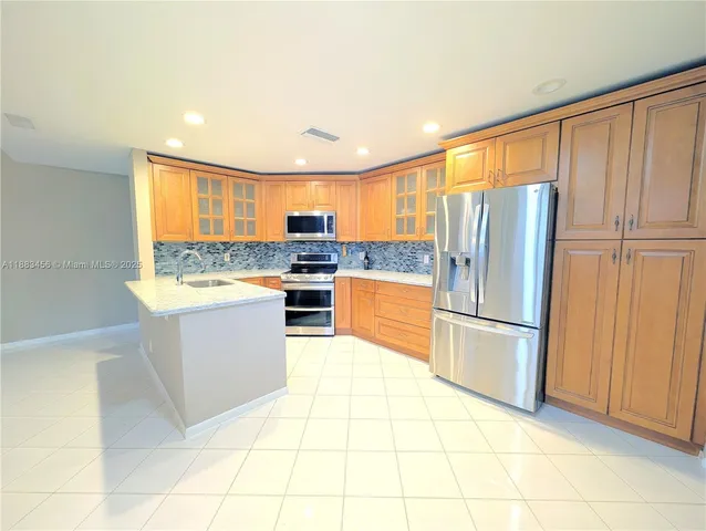 a kitchen with a refrigerator a stove top oven and cabinets