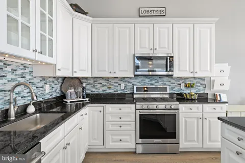 a view of a kitchen with a stove wooden floor windows and a kitchen view