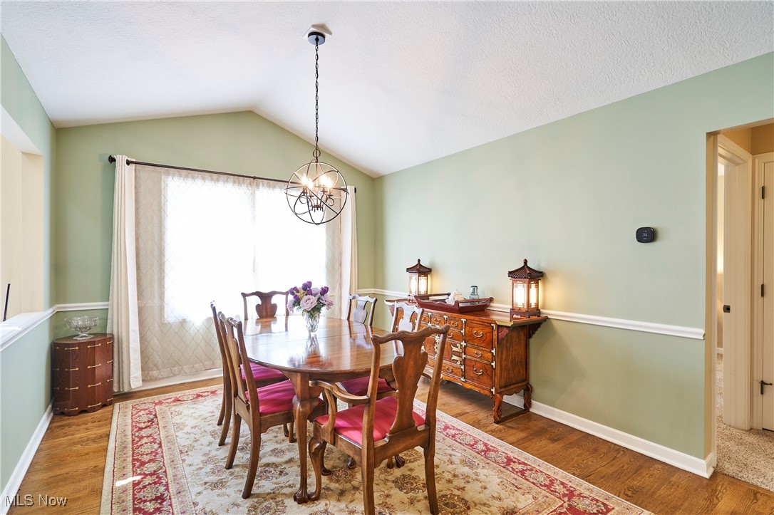 4535 Pinewood Path Akron, OH 44321 - Photo 10 of 27 Dining area featuring a chandelier, wood finished floors, and lofted ceiling