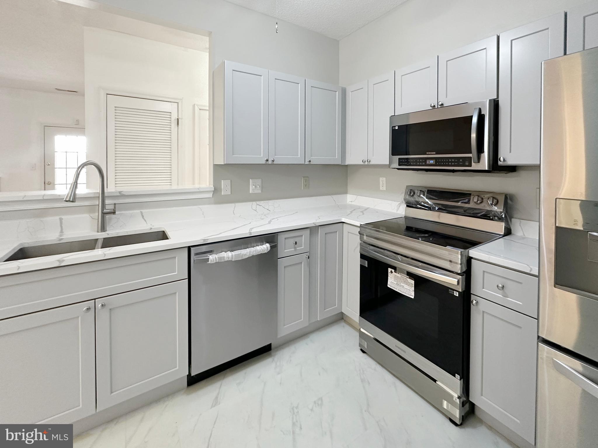 7205 Bogley Road, Unit 202 Baltimore, MD 21244 - Photo 2 of 11 a kitchen with white cabinets stainless steel appliances and sink