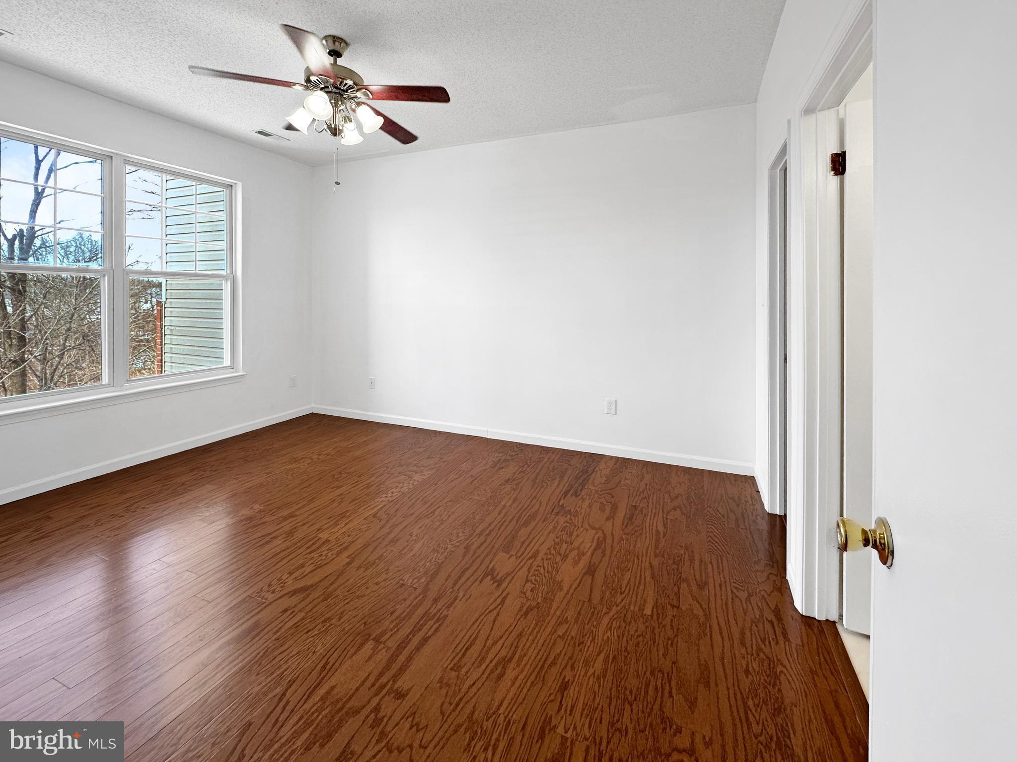 7205 Bogley Road, Unit 202 Baltimore, MD 21244 - Photo 7 of 11 an empty room with wooden floor chandelier fan and windows