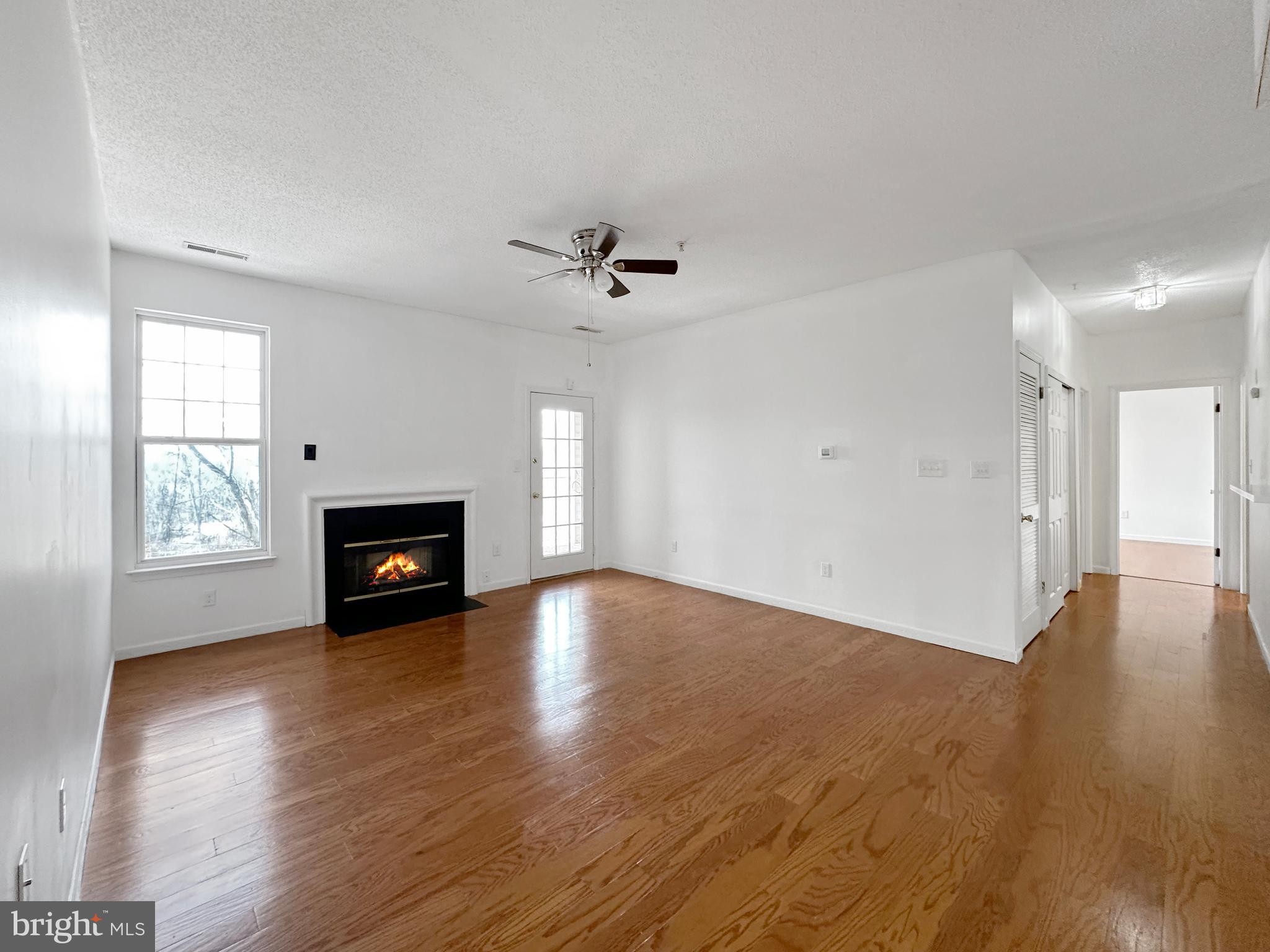 7205 Bogley Road, Unit 202 Baltimore, MD 21244 - Photo 10 of 11 a view of an empty room with a fireplace and wooden floor